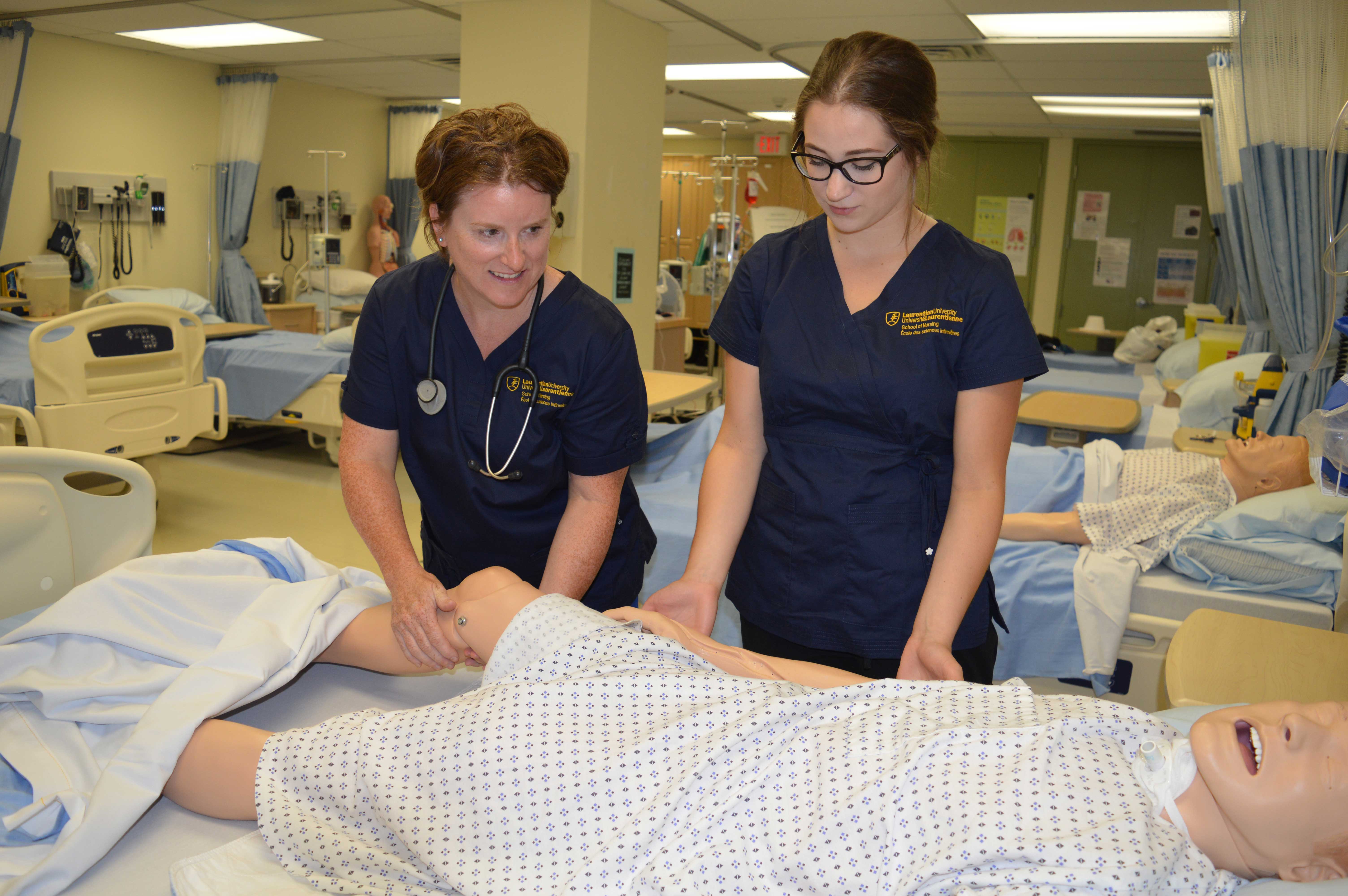 Étudiants en soins infirmiers travaillant avec un mannequin dans un laboratoire clinique.